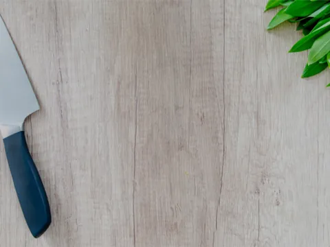 A clean, empty worktop with a chef's knife and fresh herbs